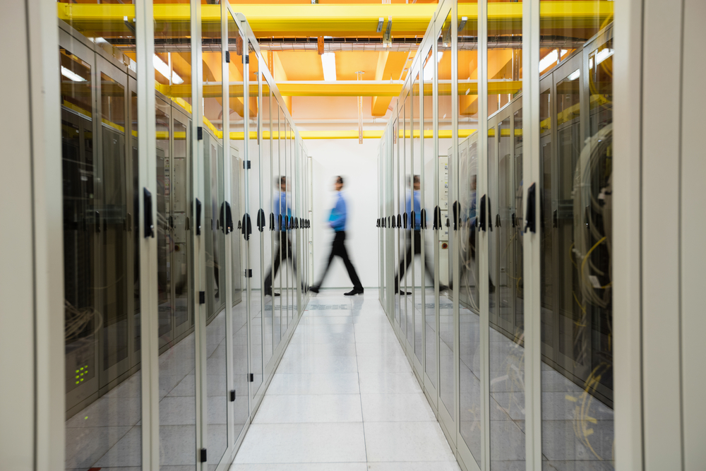 Technician walking in hallway of server room Technician walking in hallway of server room